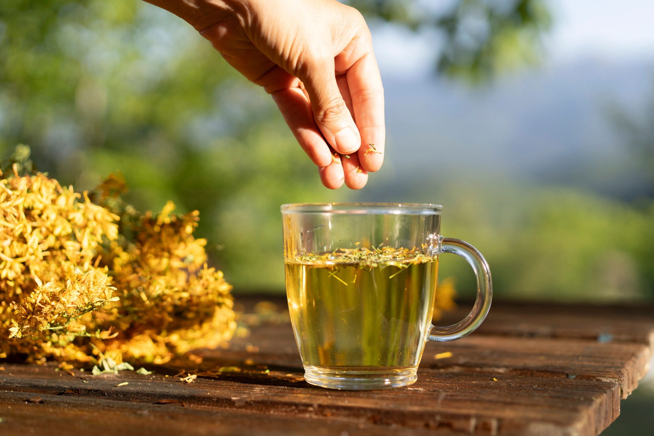 Hand adding herbs to a cup of tea