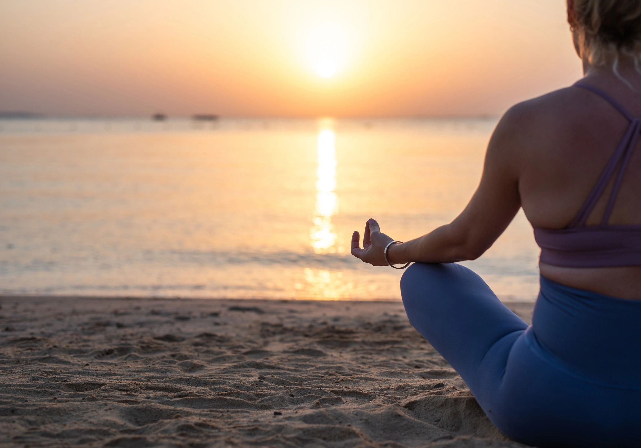 Woman meditating on a beach at sunrise